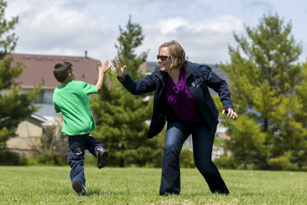 Dr. Meghann Lloyd on a field high-fiving a little boy.