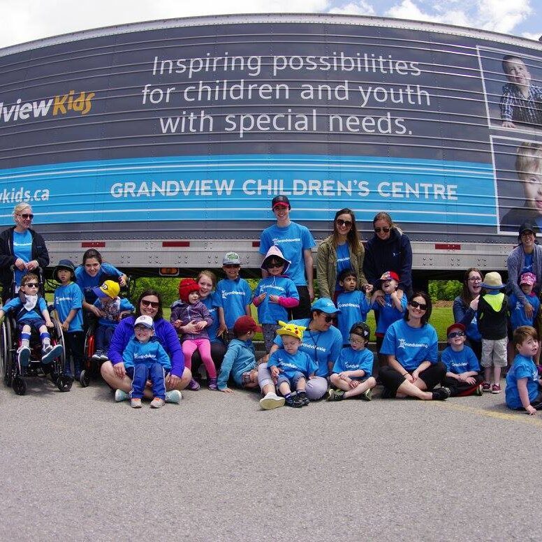 Grandview kids posing in front of a truck with a Grandview banner spread across it