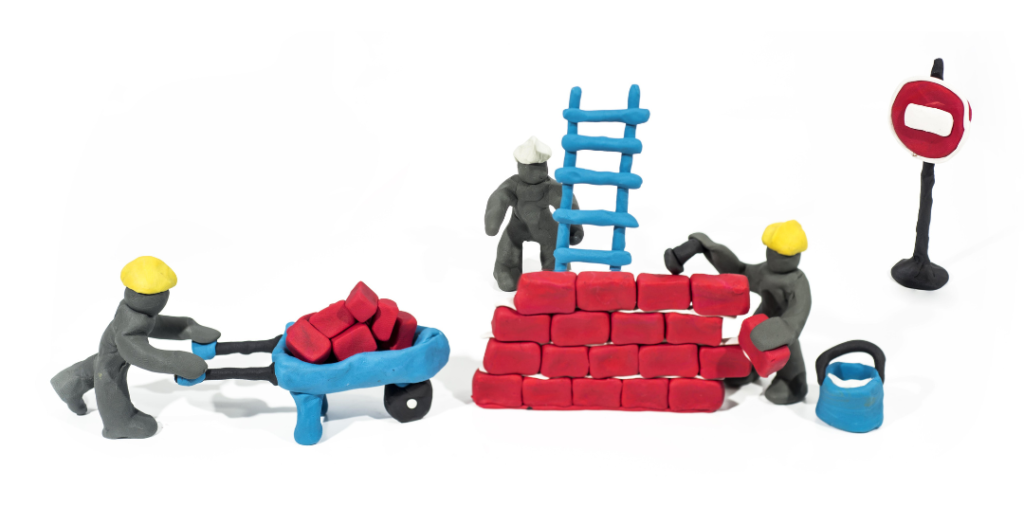 An image of plasticine construction workers building a wall made out of red plasticine bricks.