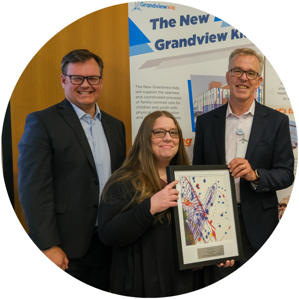 Karen J., Grandview Kids Speech-Language Therapy Assistant, posing with Jeremy Harness and Tom McHugh as she accepts her "Power of One" award.
