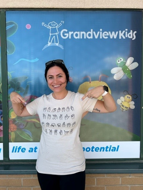 Nicole N., pointing to her white t-shirt which has the alphabet in American Sign Language (ASL).