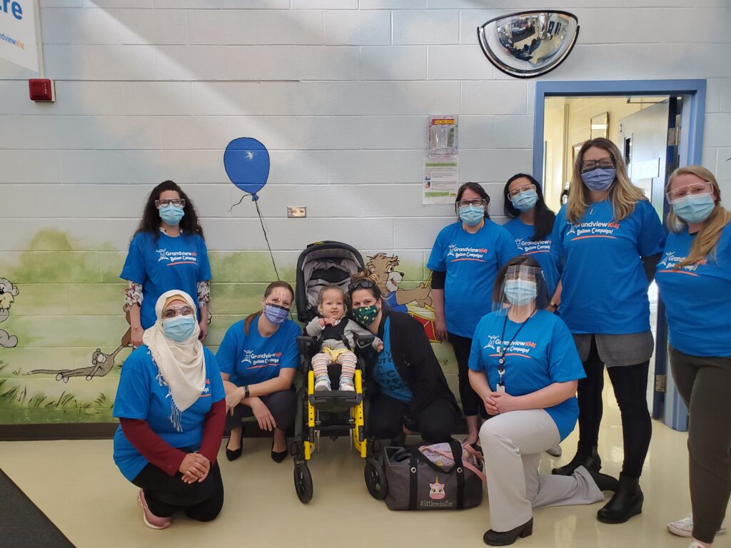 Members of the Complex Care Program multi-disciplinary team posing with Zoe–the first child to access care through the program.