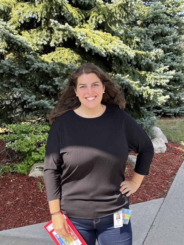 Meghan P is a white woman wearing a black shirt. She is standing in front of green trees. Meghan is a Special Education Teacher and Literacy Coach at Campbell Children’s School (CCS).