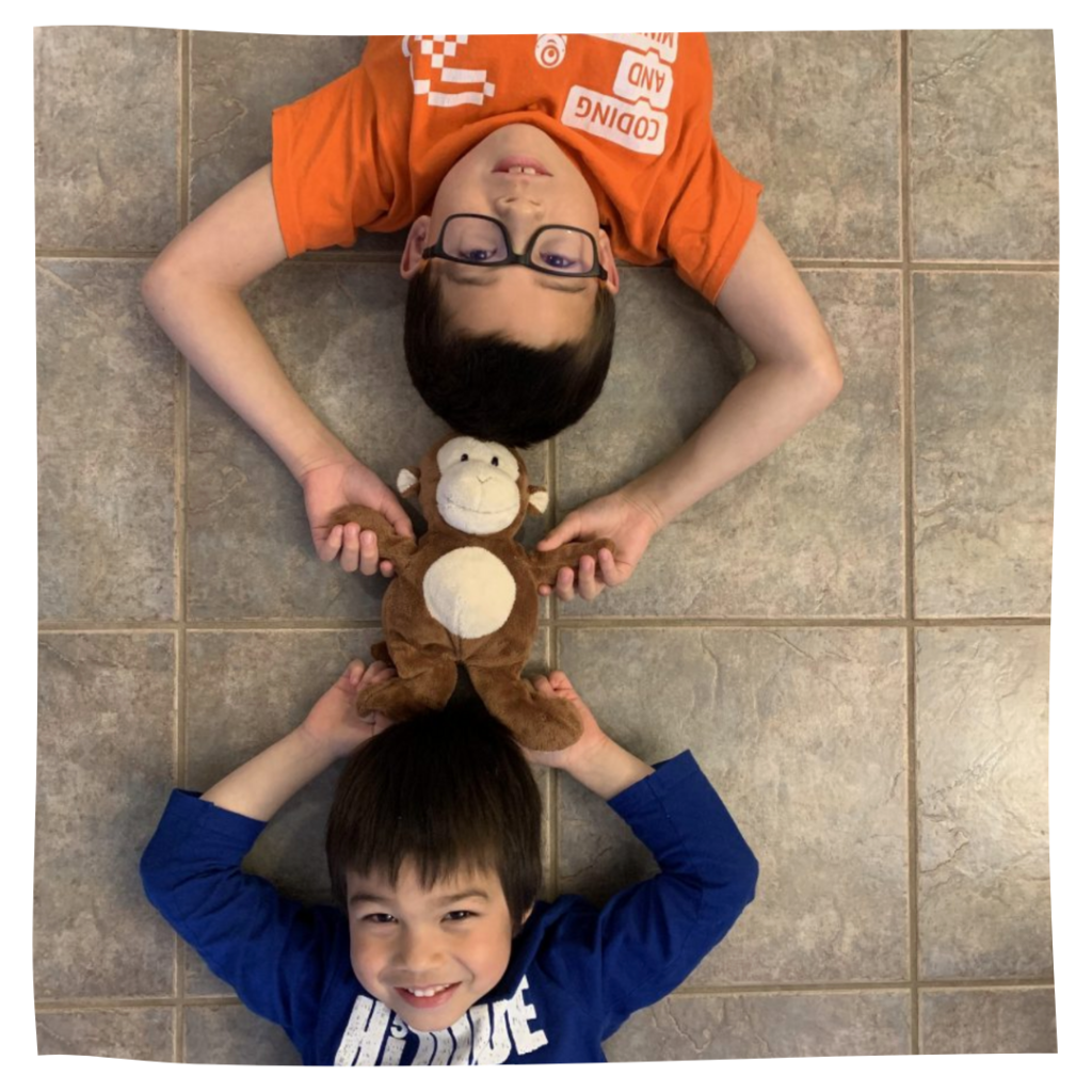 Two boys on the floor practicing the head-to-head rolling technique. 