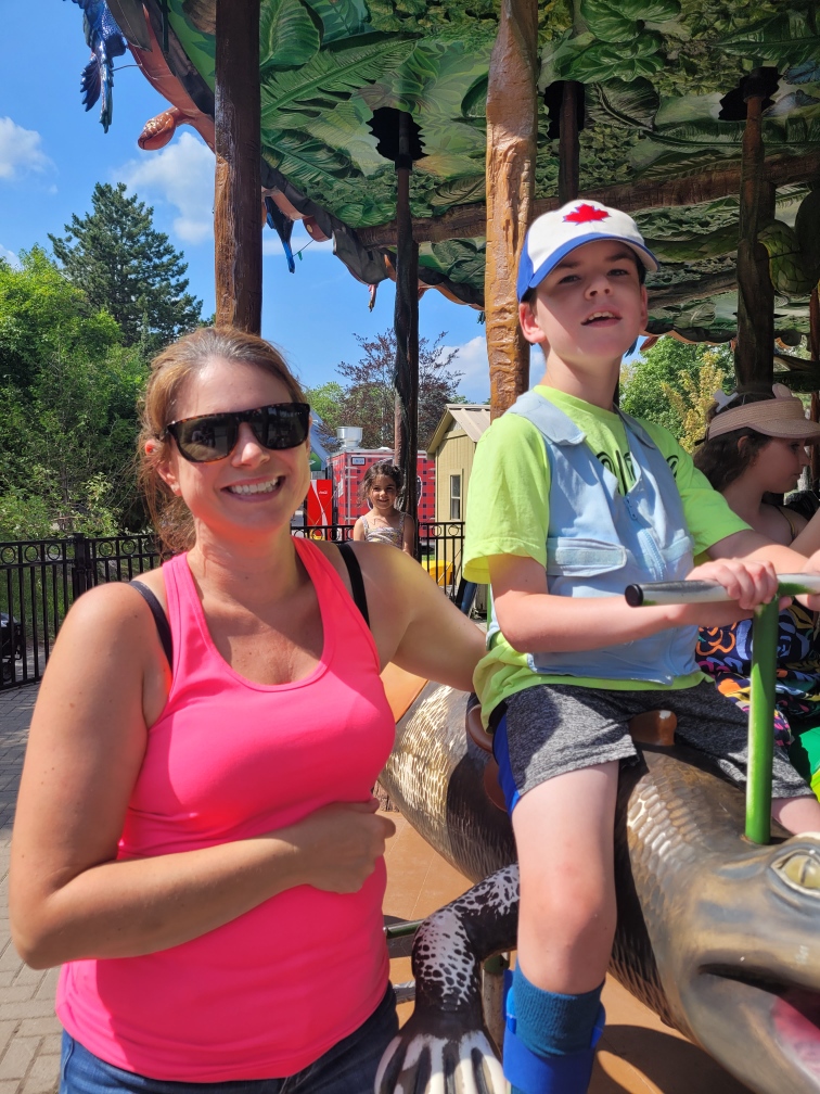 Jacki beside Colton as he is sitting on animal ride.