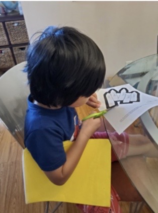 Boy cutting out an image with green scissors.