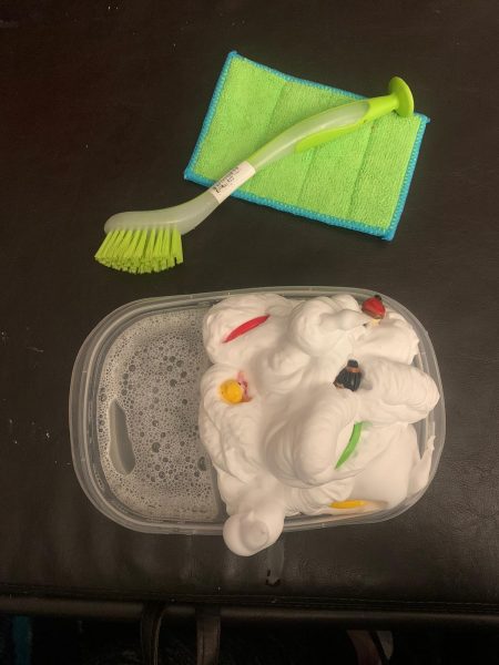 A plastic tub of soapy water with various toys and tools.  