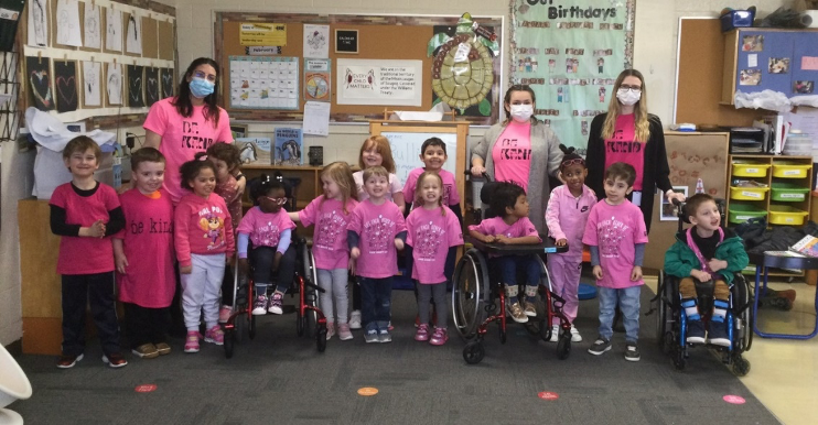 A group photo of Campbell Children's School educators and students posing in a classroom wearing pink t-shirts.
