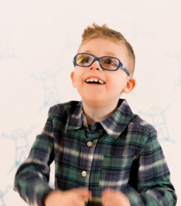 I smiling Weston is wearing a plaid button-up shirt with glasses. 